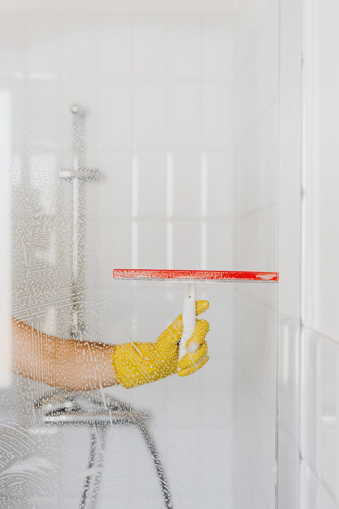 Crop person cleaning glass shower unit